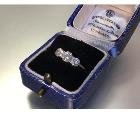 A three stone diamond ring, early 20th century, the three graduated round brilliant-cut stones on an 18ct yellow gold band. C