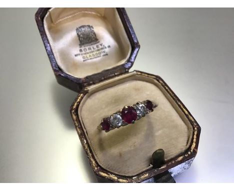 A ruby and diamond five-stone ring, early 20th century, scroll-claw set with three graduated round-cut rubies spaced by a pai