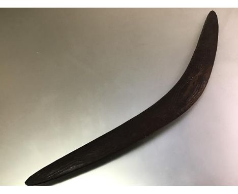 An Aboriginal war boomerang, carved to one side with a sinuous snake-like design. Length 74cm