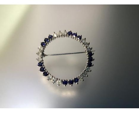 A diamond and sapphire brooch, of hoop form, mounted with bands of three round brilliant-cut diamonds spaced by three round-c