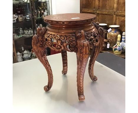 A Chinese carved hardwood vase or jardiniere stand, the circular top carved with a dragon within a Greek Key border, above a 