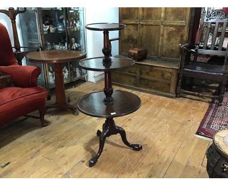 A George III mahogany three tier dumbwaiter, the graduated tiers joined by a turned baluster standard, raised on a hipped tri