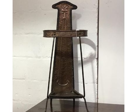 An Arts &amp; Crafts copper and wrought-iron stick stand, c. 1900, the tapering hammered copper rear panel chased with a styl