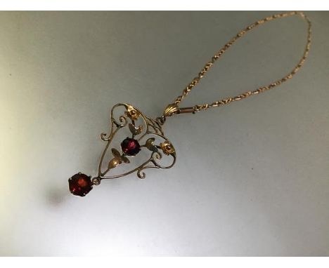 A ruby pendant in the Art Nouveau taste, of open wirework, claw-set with two round-cut rubies and further set with flowerhead