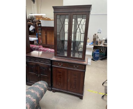 A 20th century mahogany bookcase, with a moulded dentil cornice above a pair of glazed doors with glazing bars, the base with