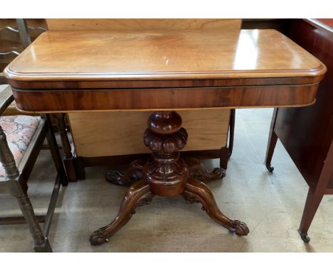 A Victorian mahogany card table the rectangular hinged top with rounded corner with a baize interior on a shaped column and f