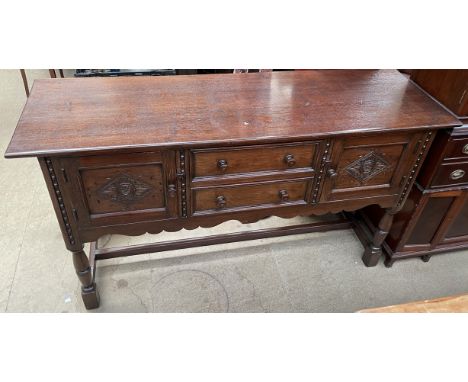 A 20th century oak sideboard with a rectangular top above a pair of central drawers and cupboards on ring turned legs