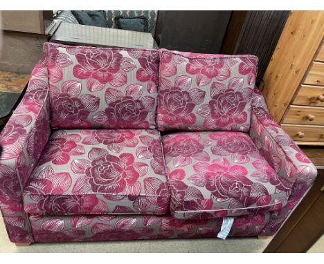 A floral decorated two seater sofa bed