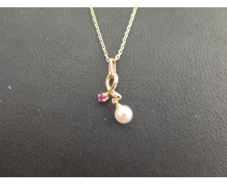 A cultured pearl and ruby pendant - Suspended from a box-link chain - Stamped K14 - Length of pendant 2cms - Length of chain 