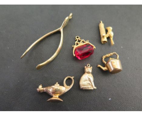 A 9ct gold wishbone pendant - Together with an assortment of five charms - All with marks indicating 9ct gold - Total weight 