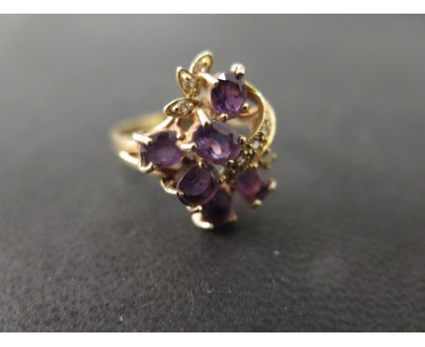 An 18 ct gold diamond and amethyst dress ring - pretty design to imitate a posy of violets with a ribbon, set with six oval a