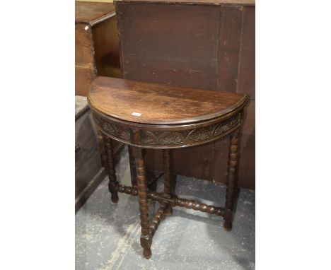 A 17th Century style oak folding games table, early 20th CenturyHaving a carved frieze raised upon bobbin turned supports. 