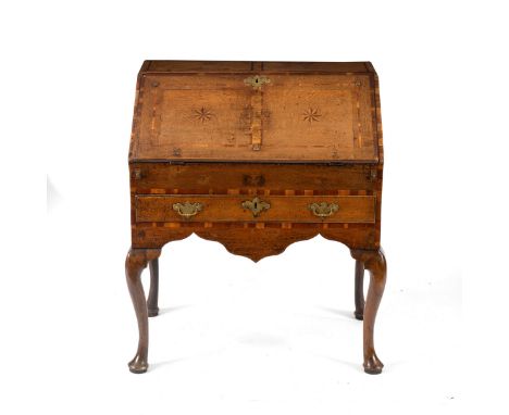 A George III provincial oak bureau, the moulded crossbanded fall-flap inlaid with two compass style medallions enclosing a fi