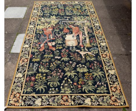A 20th Century tapestry depicting metal forgers, 325cm x 170cm/Note: the original woven circa 1500, this millefleurs tapestry