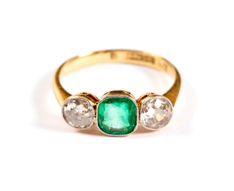 An emerald and diamond three-stone ring, the emerald flanked by diamonds of approximately 0.3ct in a millegrain platinum sett