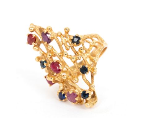 A sapphire and ruby ring in the style of Andrew Grima, the textured openwork 18ct yellow gold setting set with scattered ston