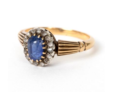 A sapphire and diamond cluster ring, the oval sapphire to a border of rose cut diamonds claw set to an unhallmarked yellow pr