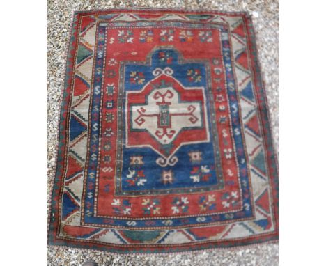 A Kazak prayer rug with centre medallion on an architectural style blue ground, within a red field, with flower head medallio