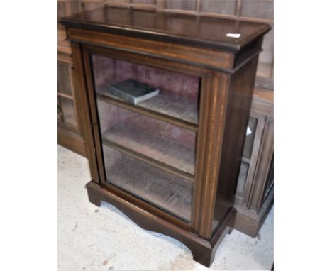 An Edwardian mahogany and satinwood banded side cabinet with single glazed door enclosing shelving, raised on a bracket foot 