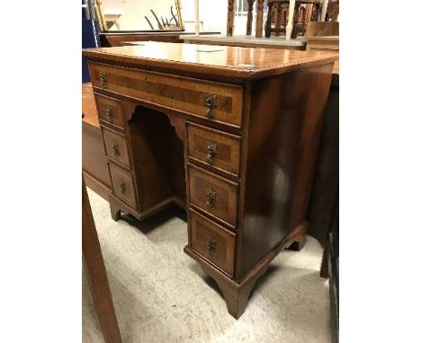 A burr walnut kneehole desk in the early 18th Century manner, the top feathered and crossbanded within a moulded edge over a 