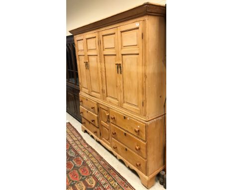A 19th Century pine housekeeper's cupboard with two pairs of fielded panel cupboard doors over a central drawer flanked by tw
