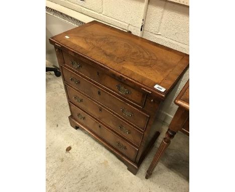 A walnut bachelor's chest in the early 18th Century manner, the fold-over top feathered and cross-banded and resting on two l