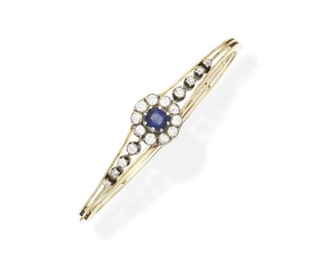 SAPPHIRE AND DIAMOND SET BANGLE, CIRCA 1890The cushion-cut sapphire within a cushion-shaped diamond surround, between similar