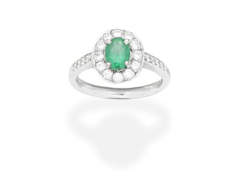 EMERALD AND DIAMOND CLUSTER RING  2009The oval-cut emerald within a brilliant cut diamond surround and shoulders, mounted in 