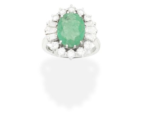 EMERALD AND DIAMOND CLUSTER RINGThe oval-cut emerald within a brilliant and tapered baguette-cut diamond surround, diamonds a