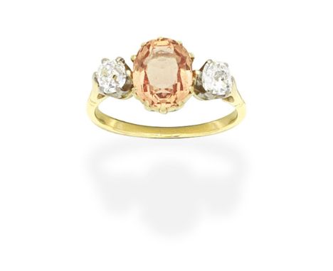 TOPAZ AND DIAMOND RINGThe oval-cut orange topaz between cushion-shaped diamonds, ring size approx. L½For further information 