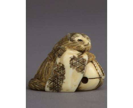 A 19th century Japanese netsuke from Meiji period. Not signed. In carved elephant ivory portraying Tanuki resting over a moku