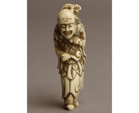 An 18th century Japanese netsuke from Edo period. Not signed. In carved elephant ivory portraying a standing Gama Sennin carr