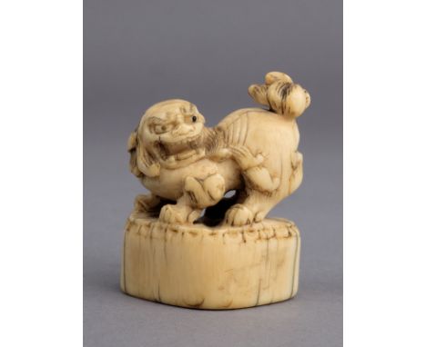 An 18th century Japanese netsuke from Edo period. Not signed. In carved elephant ivory portraying a shishi on a pedestal, 39x