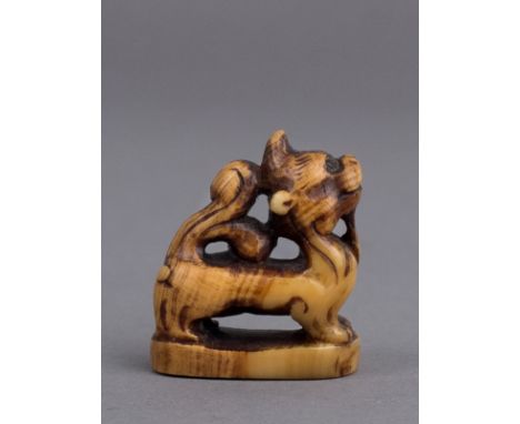 A 19th century Japanese netsuke from Edo period. Not signed. In carved elephant ivory portraying a sishi on a pedestal, 25,3x