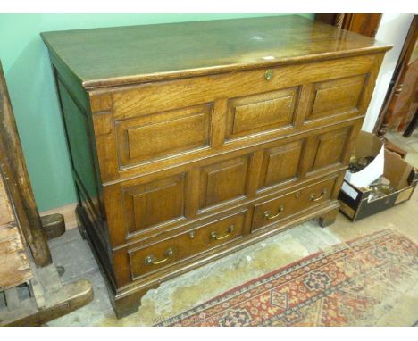 A late 19th c. Oak Mule Chest with two plank lid over seven panel front with two drawers, panelled ends, brass escutcheon and