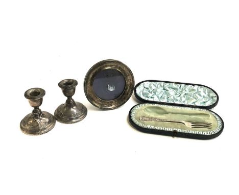 A pair of short loaded silver candlesticks, one af, Birmingham 1949, a small circular silver picture frame, 12cmD, and a case