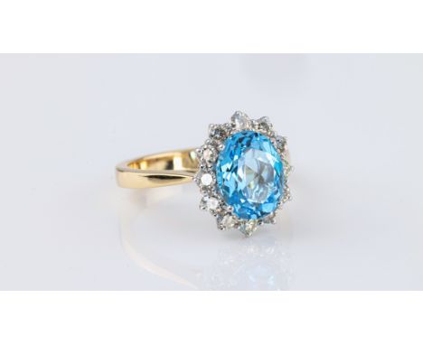 An 18ct yellow gold, blue topaz and diamond cluster ring, the 3.55ct oval cut topaz within a border of twelve brilliant cut d