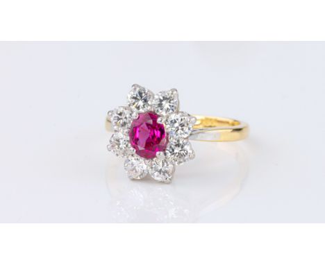 An 18ct gold, platinum, ruby and diamond cluster ring, the pinkish-red oval cut ruby, 6 x 5mm., within a border of eight bril