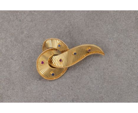 A vintage 18ct yellow gold, ruby and sapphire brooch, stamped 'BTF 0750' to clasp, in the form of a fluted, knotted ribbon wi