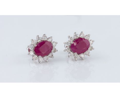 A pair of 18ct white gold, ruby and diamond cluster earrings, the two oval cut rubies, total 2.68ct, each within a border of 