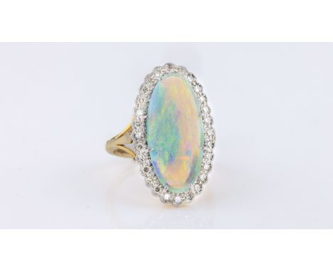 An 18ct gold, platinum, opal and diamond cluster ring, hallmarked Birm. 1989, the elongated oval cabochon opal, 21.5 x 10mm.,