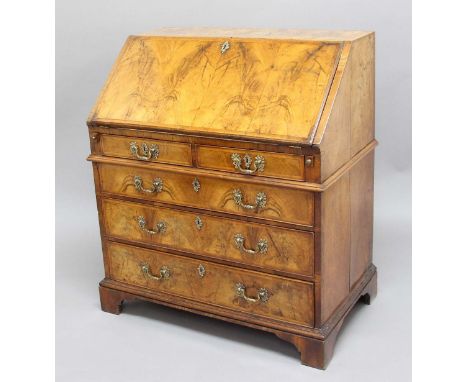 GEORGE II WALNUT BUREAU, the feather banded fall front enclosing a fitted interior, above two short and three long, cockbeade