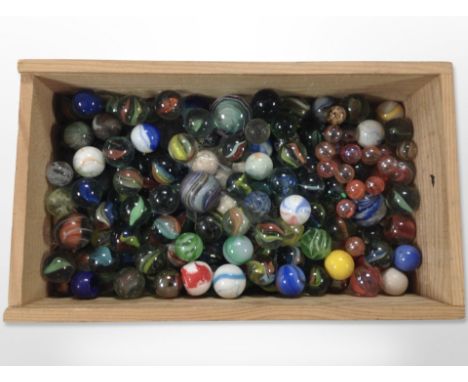A pine crate containing vintage glass marbles, some larger examples 