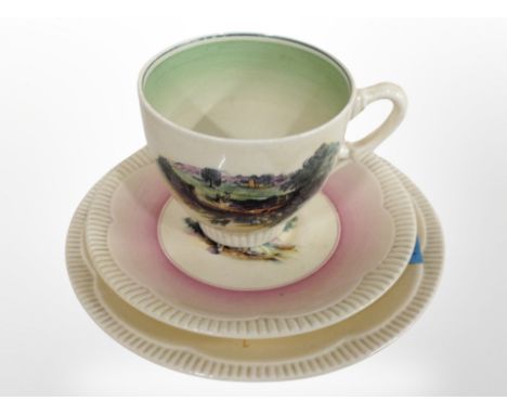 A Clarice Cliff Newport Pottery teacup and two graduated saucers decorated with landscapes.