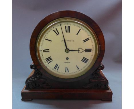 A 19th century mahogany mantle clock by John Walker, the round enamel dial with roman numerals, the case carved with scrollin