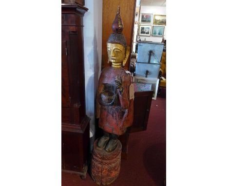A large Oriental hardwood statue of Buddha, having gilt painted face and red painted body, raised on floral carved base, H. 1