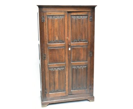 An early 20th century oak wardrobe, the pair of linen fold carved doors enclosing rail, raised on bracket feet, height 191cm,