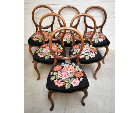 A set of six Victorian walnut balloon back salon chairs, raised on cabriole supports, the seat cushions upholstered with flor