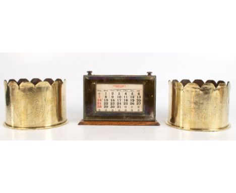 MANCO; an oak framed desk calendar with silver plated mounts, length 21cm, and two brass trench art shells each with carved S