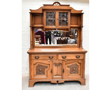 An Arts and Crafts golden oak high back dresser with two curved doors with leaded bowed glass panels, flanked by open shelves